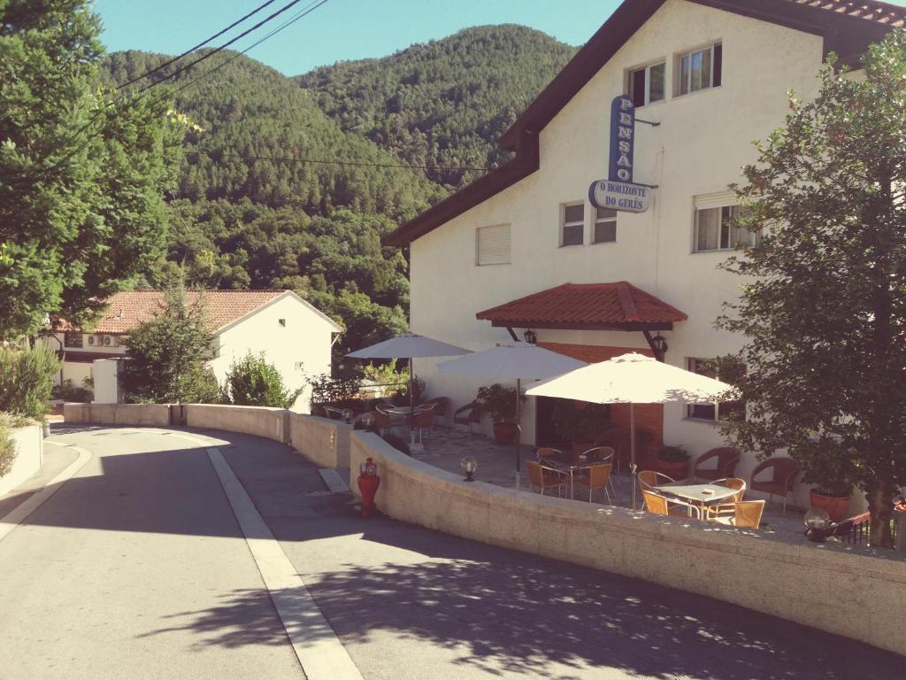 una posada con mesas y sombrillas delante en Horizonte do Geres, en Gerês