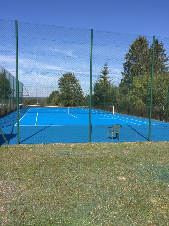 una pista de tenis azul con un banco. en Hotel L'Ecrin 88 Vosges en Grandvillers