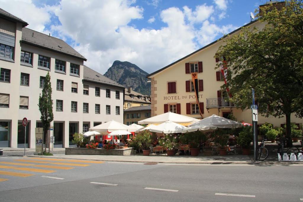 a street with buildings with tables and umbrellas at Hotel du Pont in Brig