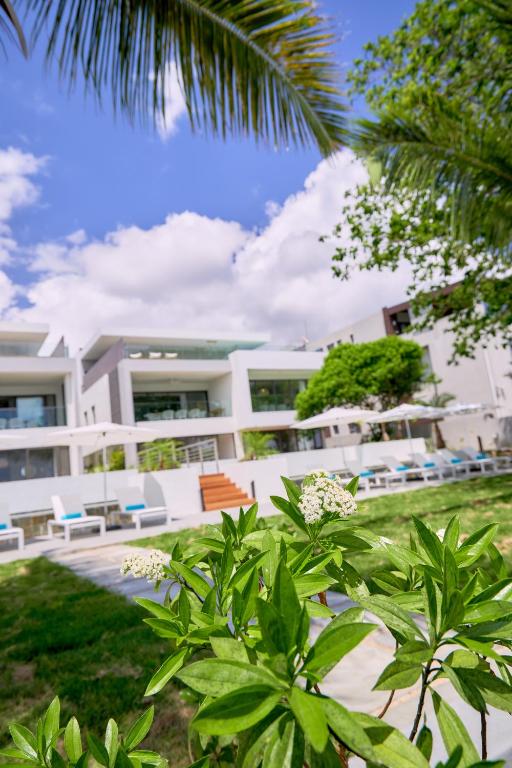 a large white building with chairs and trees at Les Estivales Beachfront Apartments & Penthouses by LOV Mauritius in Trou aux Biches