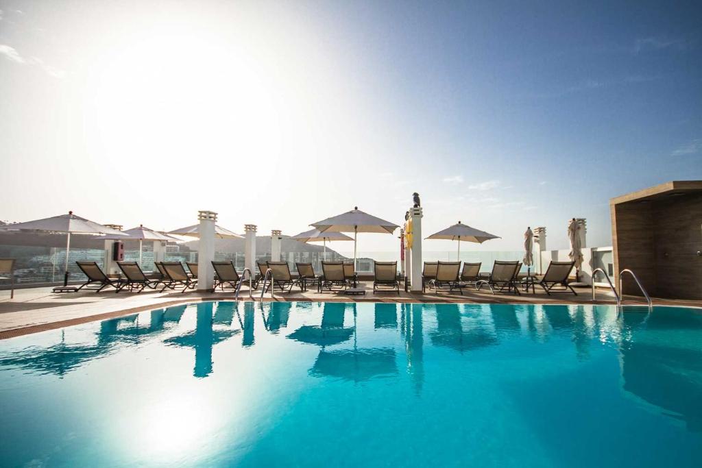 una grande piscina con sedie e ombrelloni di IG Nachosol Premium Apartments by Servatur (Adults Only) a Puerto Rico de Gran Canaria