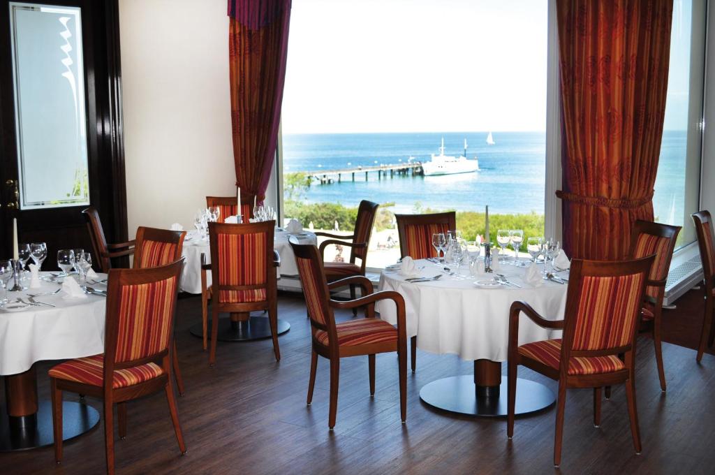 a restaurant with tables and chairs with a view of the ocean at Morada Strandhotel Ostseebad Kühlungsborn in Kühlungsborn