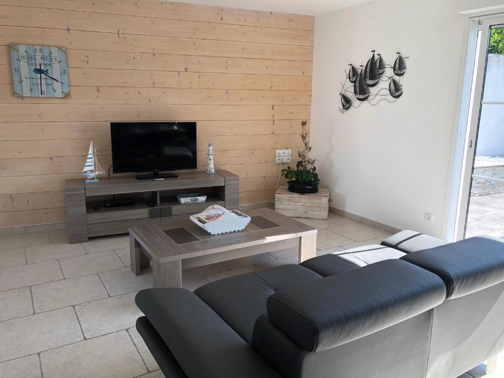 a living room with a couch and a tv at La petite rétaise in La Flotte