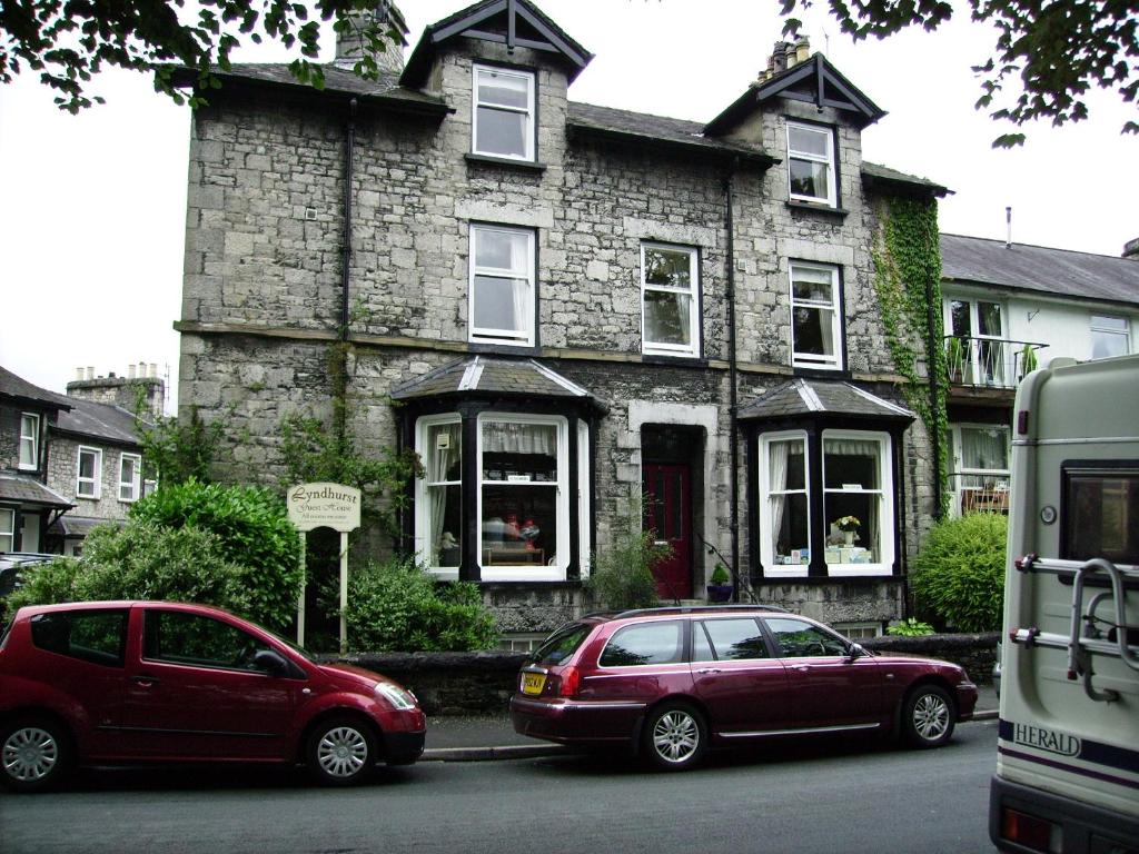 two cars parked in front of a stone house at Lyndhurst Guest House in Kendal