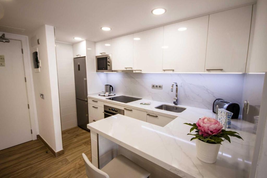 a kitchen with white cabinets and a counter with a flower at IG Nachosol Atlantic & Yaizasol by Servatur - Adults Only in Puerto Rico de Gran Canaria