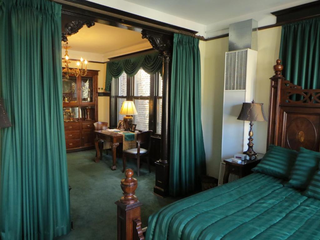 Schlafzimmer mit grünen Vorhängen, einem Bett und einem Schreibtisch in der Unterkunft The Polo Inn Bridgeport U.S.A. in Chicago