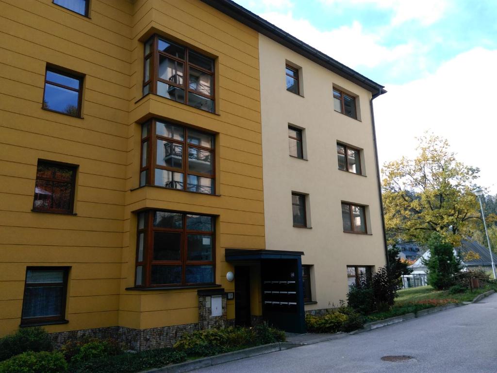 un bâtiment jaune avec des fenêtres noires sur une rue dans l'établissement Apartmán Maruška, à Janské Lázně