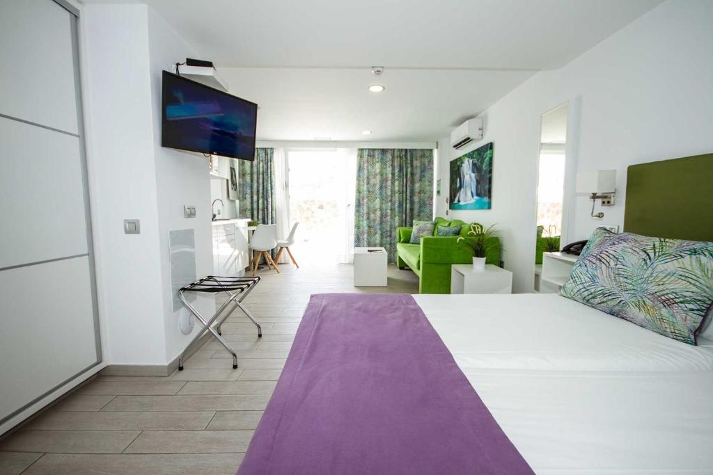 a room with a large bed and a living room at IG Nachosol Atlantic & Yaizasol by Servatur - Adults Only in Puerto Rico de Gran Canaria