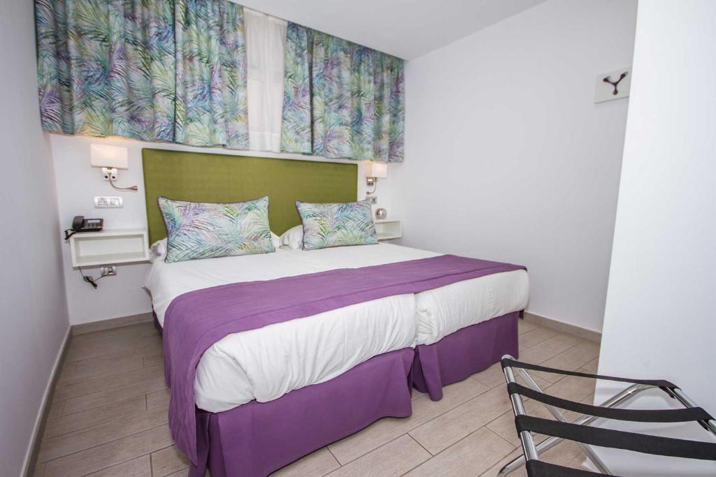 a bedroom with a large bed with purple sheets and a window at IG Nachosol Atlantic & Yaizasol by Servatur - Adults Only in Puerto Rico de Gran Canaria
