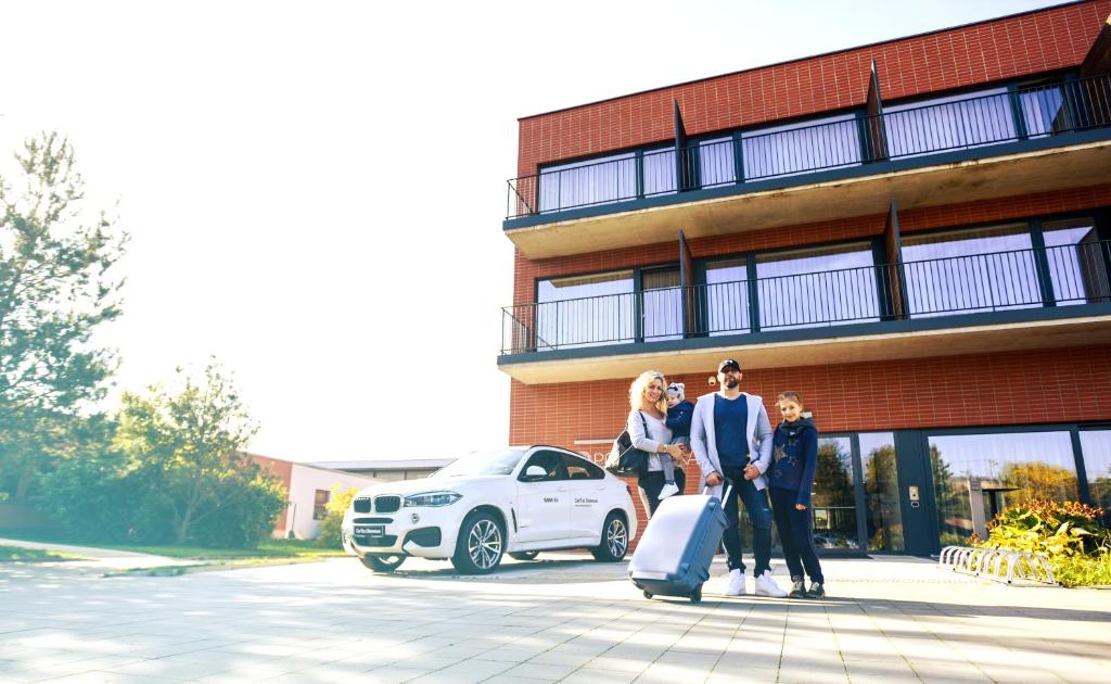 un groupe de personnes debout devant un bâtiment avec une voiture dans l'établissement Hotel S-PORT Véska, à Dolany