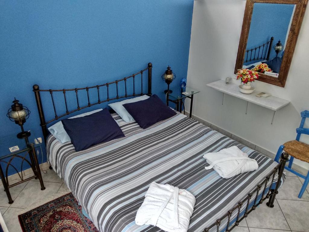 a bedroom with a bed with blue walls and a mirror at Seafarer's Suite in Galaxidi