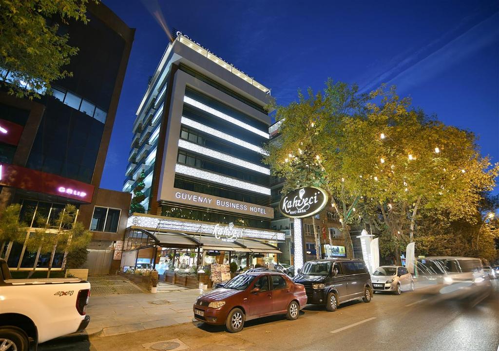 een stadsstraat met auto's die voor een gebouw geparkeerd staan bij Güvenay Business Hotel in Ankara