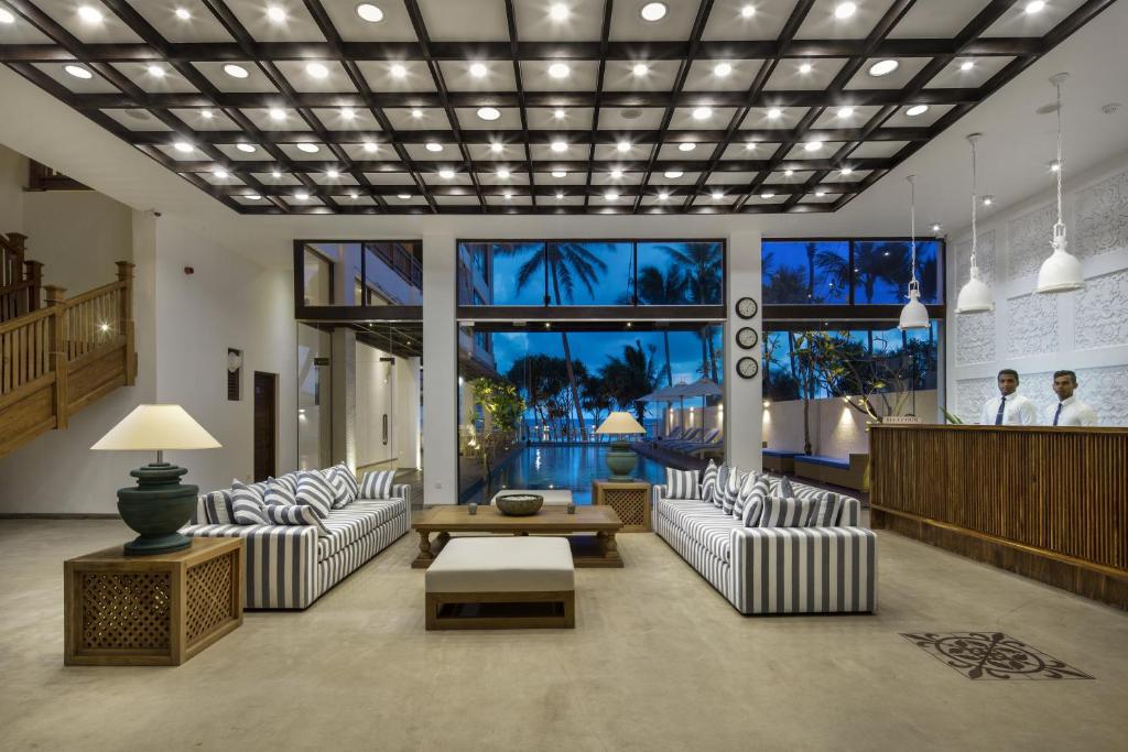 a lobby with white couches and a table and windows at Lucky Elephant Hotel in Hikkaduwa