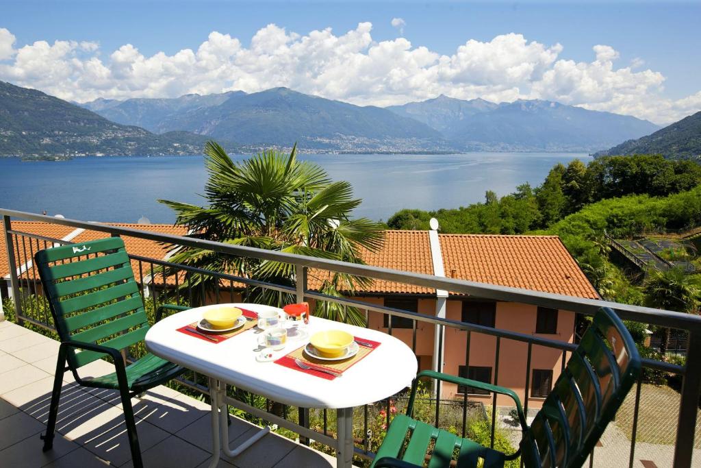 einen Tisch und Stühle auf einem Balkon mit Seeblick in der Unterkunft Residenza Arcobaleno in Pino Lago Maggiore