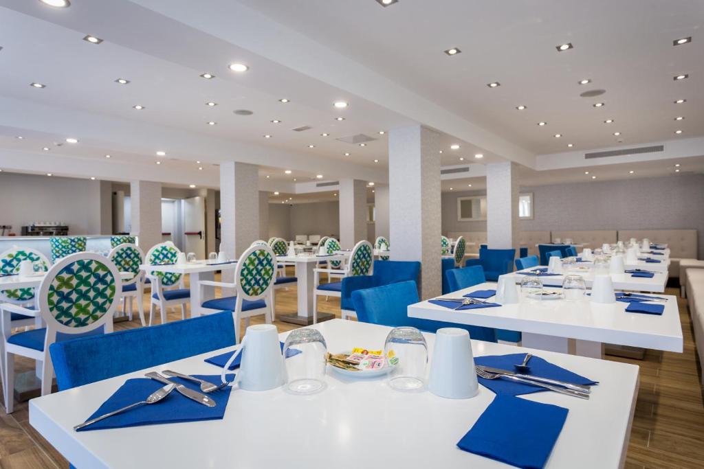 a dining room with white tables and blue chairs at IG Nachosol Atlantic & Yaizasol by Servatur - Adults Only in Puerto Rico de Gran Canaria