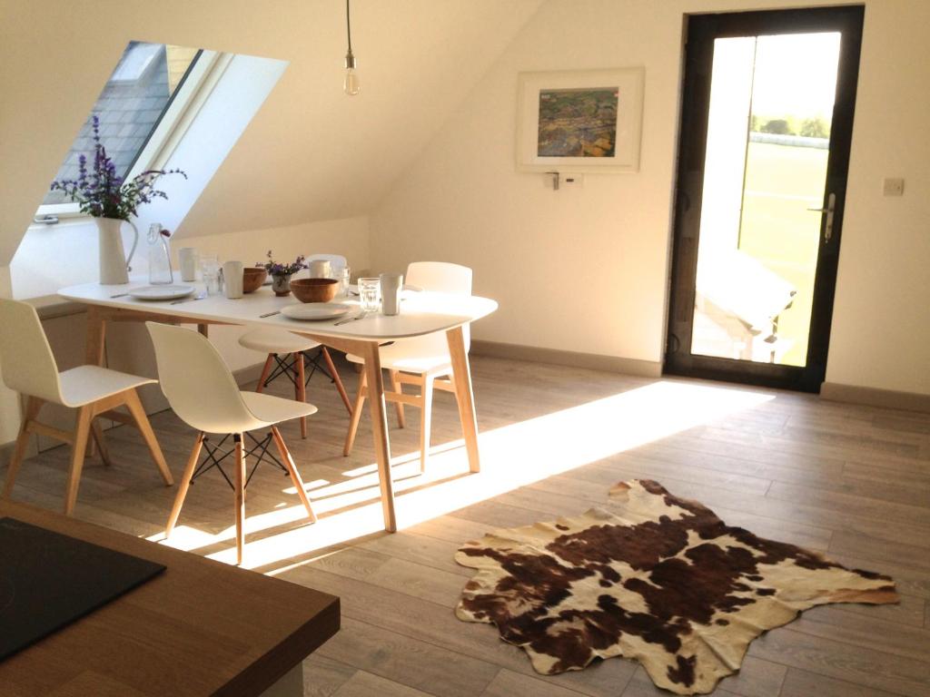 un comedor con una mesa y sillas blancas, una mesa y una alfombra en The Loft, en Pilton