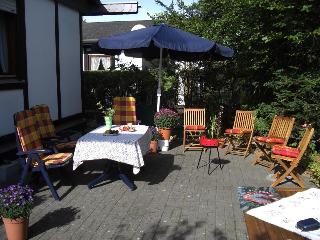 eine Terrasse mit einem Tisch, Stühlen und einem Sonnenschirm in der Unterkunft Ferienhaus EifelPur in Ahrdorf