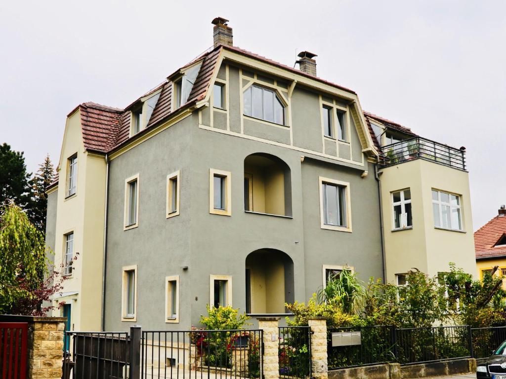 ein großes Haus mit einem Zaun davor in der Unterkunft Residenz am Dresdner Stadtwald in Dresden