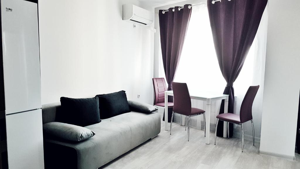 a living room with a couch and a table with chairs at Apartment Valerie walking distance to Top Center in Plovdiv