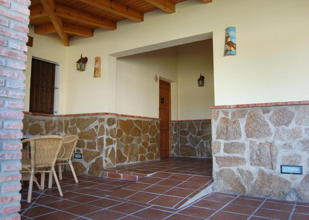 a patio with chairs and a stone wall at Residencial La Teja in Zahora