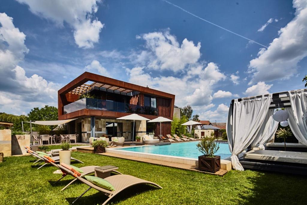 a house with a swimming pool and some lawn chairs at Butik Design Rooms in Abádszalók