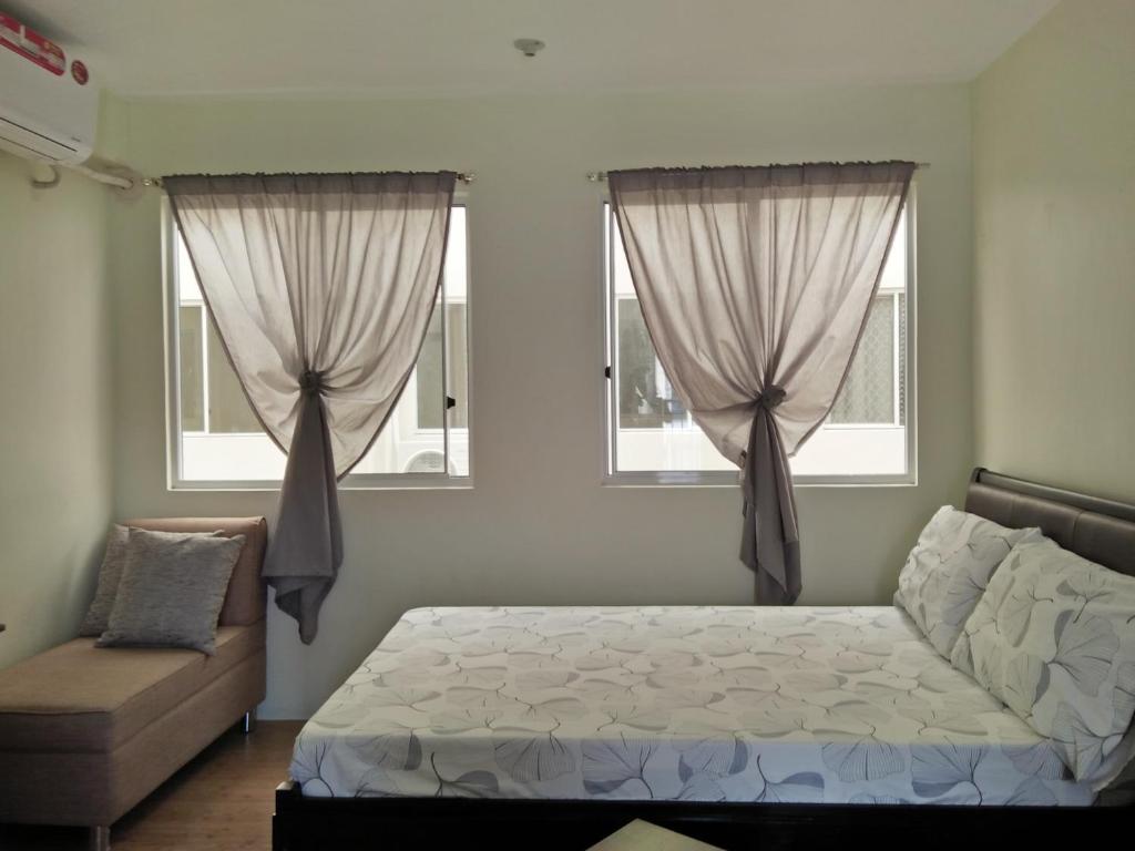 a bedroom with a bed and two windows at Stay at Sanremo Oasis Cebu in Cebu City