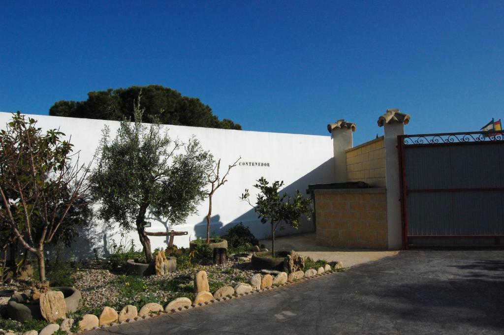 a white building with a fence and trees in a yard at Residencial La Teja in Zahora