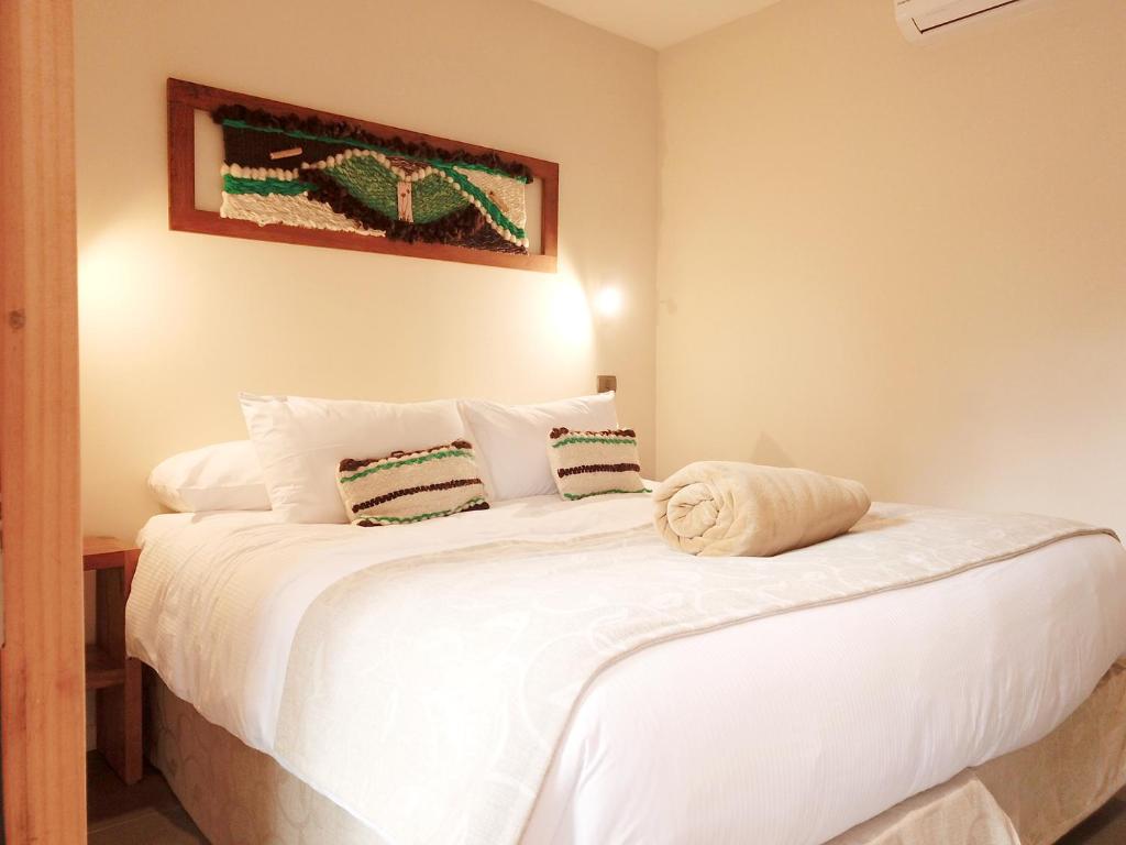 Un dormitorio con una gran cama blanca en una habitación. en Maki Hotel, en Pucón