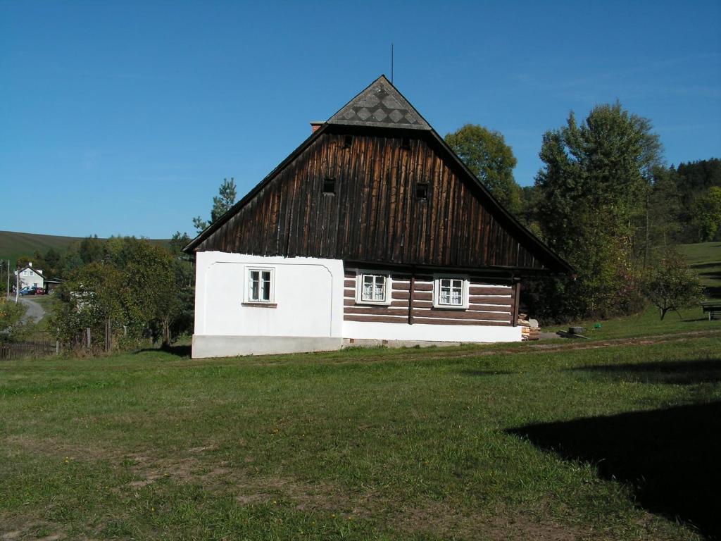 eine große Scheune mit einem Holzdach auf einem Feld in der Unterkunft Krkonosska Chalupa in Semily