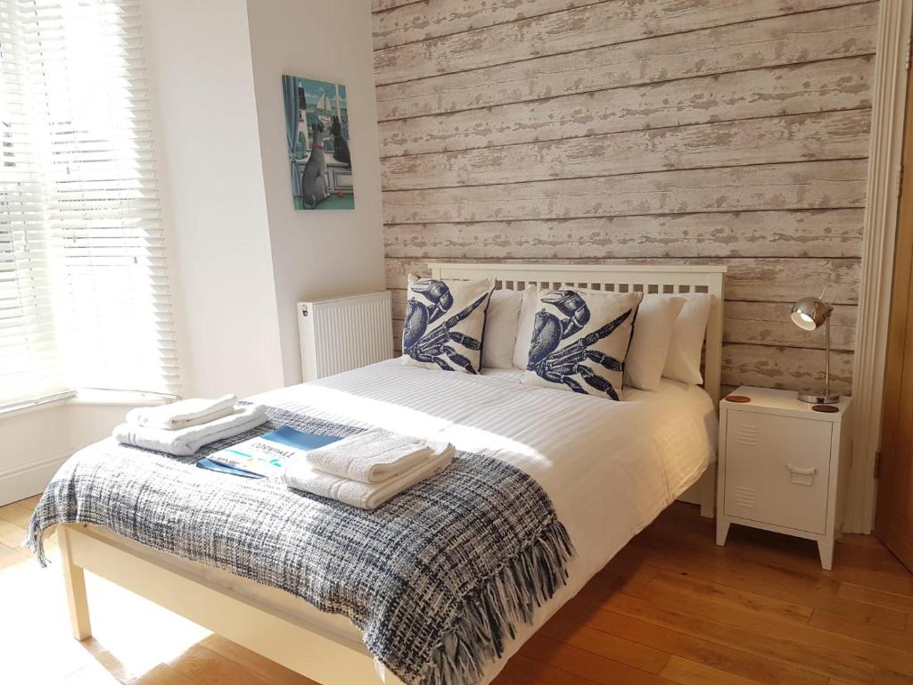a bedroom with a white bed with a wooden wall at Saltwater in St Ives