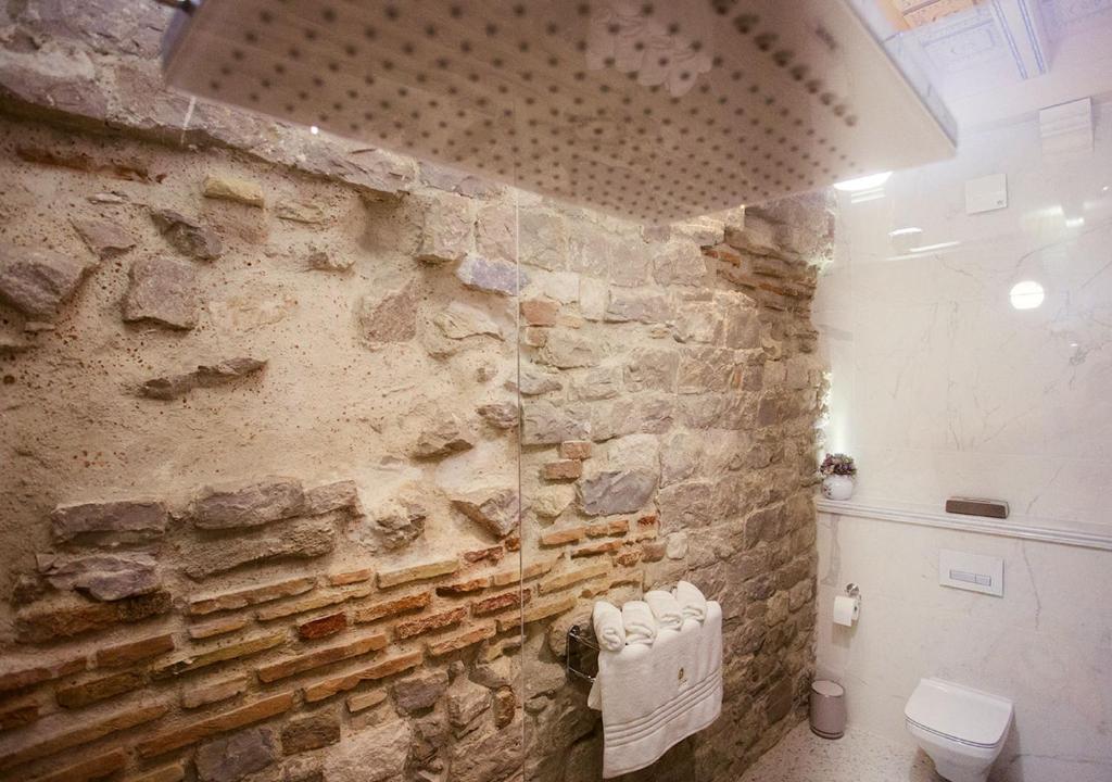 a bathroom with a stone wall and a toilet at Heritage Hotel Cardo in Split