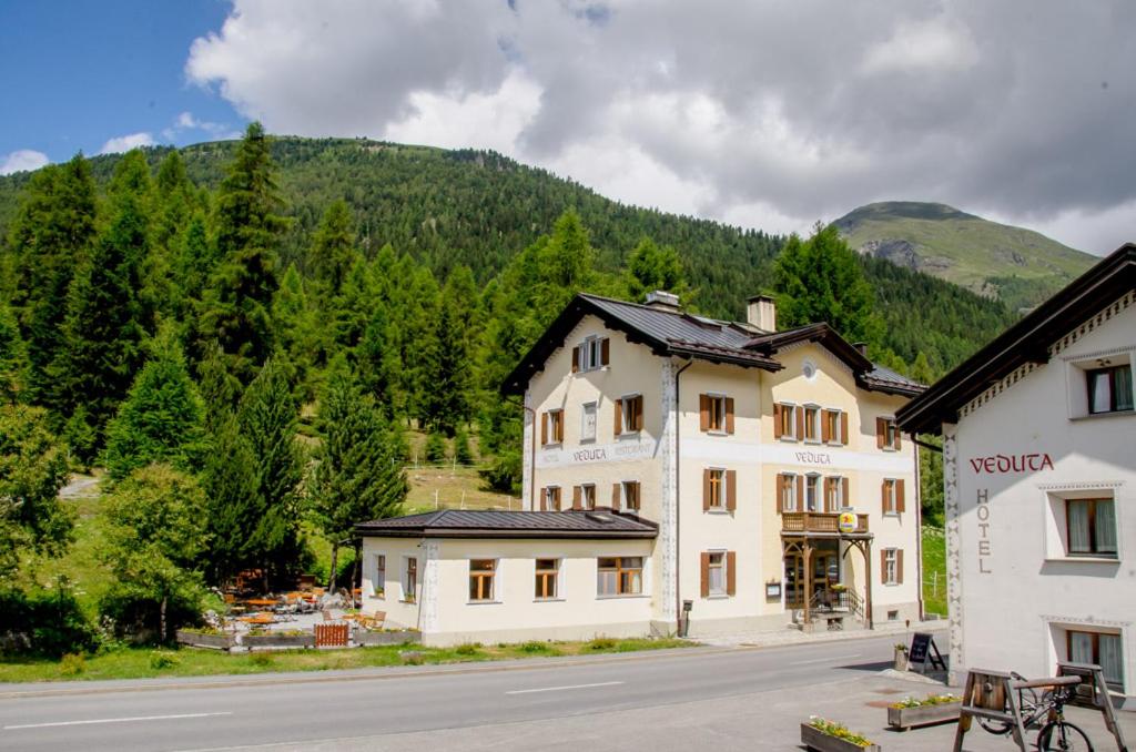 un grande edificio bianco sul lato di una strada di Hotel Veduta a Cinuos-Chel