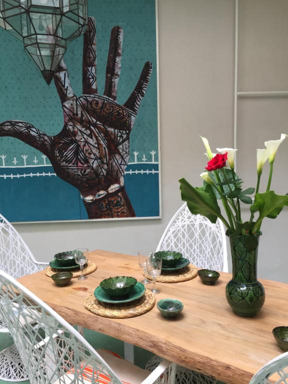een houten tafel met groene borden en een vaas met bloemen bij EDEN KAM Riad in Marrakesh