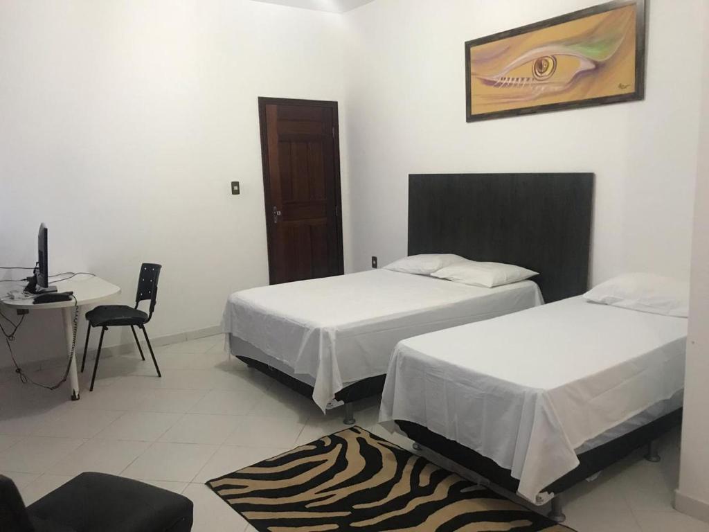 een slaapkamer met 2 bedden en een bureau met een computer bij hotel encontro das aguas in Santarém