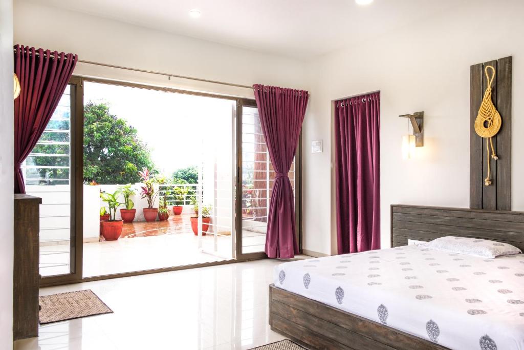 um quarto com uma cama e uma grande porta de vidro deslizante em Green Roof - Family Room em Kolhapur