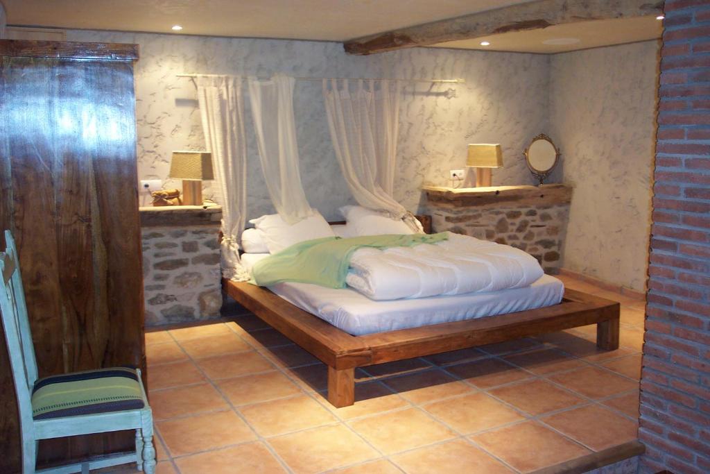 a bedroom with a bed with curtains and a chair at El Casal in Prats-de-Mollo-la-Preste