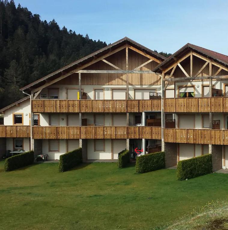 - un grand bâtiment avec une cour verdoyante devant dans l'établissement les fermes du lacs, à Gérardmer