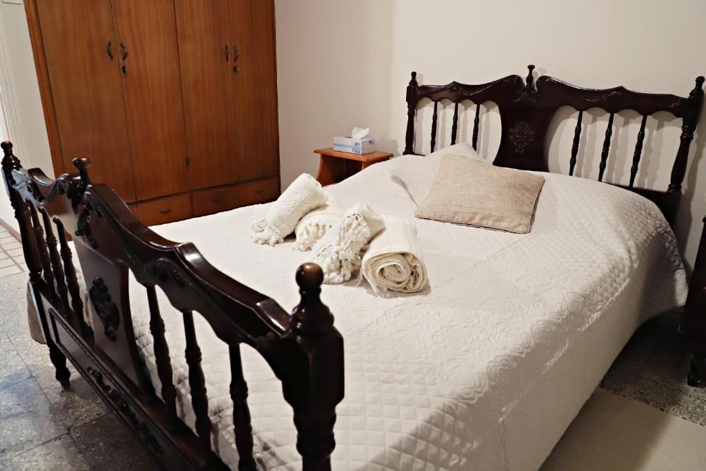 drewniane łóżko z białą pościelą i poduszkami w obiekcie Maria Court 2, Apt 32 w Larnace