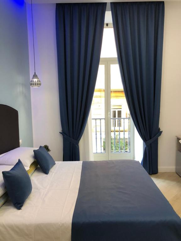 - une chambre avec un lit doté de rideaux bleus et d'une fenêtre dans l'établissement DOMO B&B, à Naples