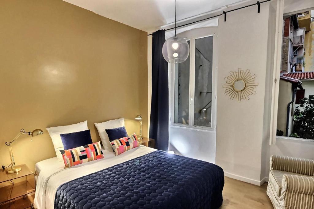 een slaapkamer met een blauw bed met kussens en een raam bij Les Appartements d'Edmond Sylvabelle in Marseille