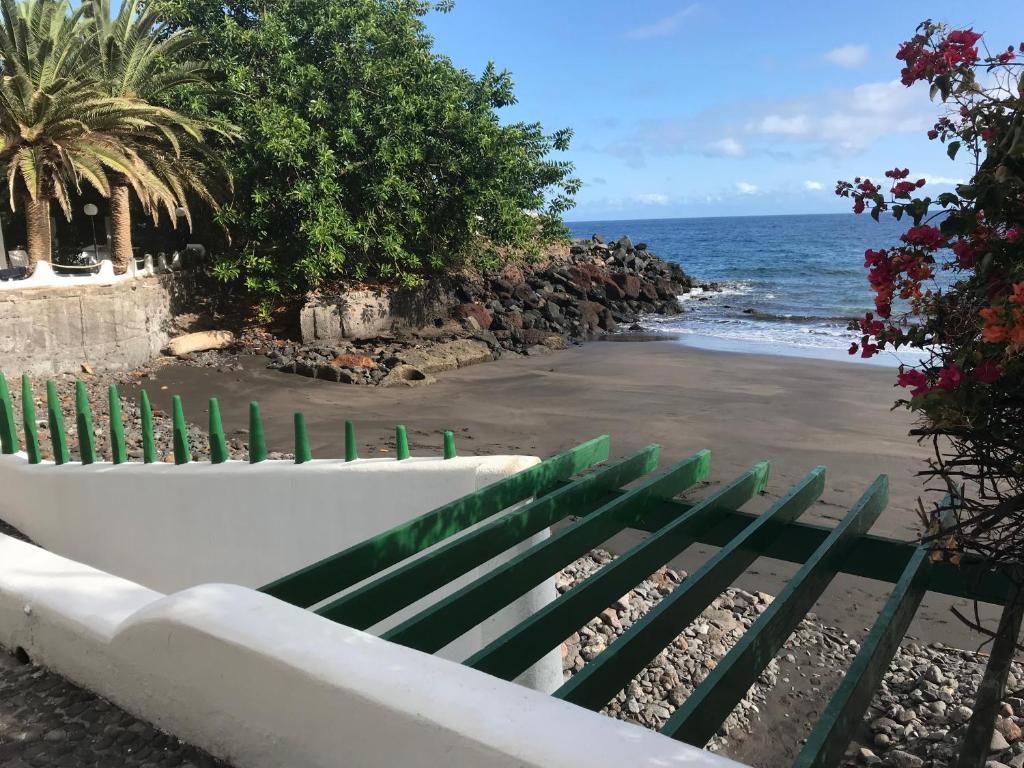 a green and white bench sitting on the beach at Apartamento Playa Chica Tenerife in San Andrés