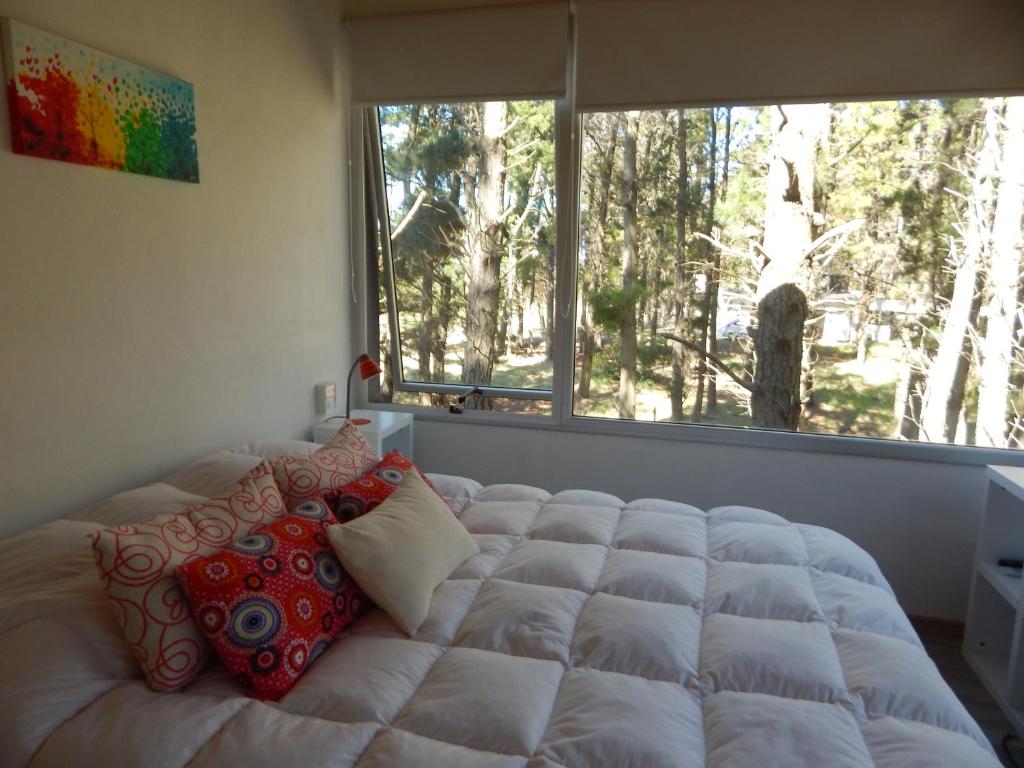 a bed in a bedroom with a large window at ILUSIONES Bosque y Mar in Mar de las Pampas