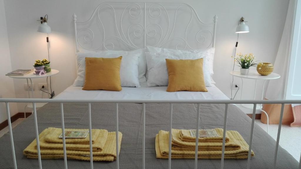 een wit bed met gele kussens en handdoeken erop bij acasadienrico in Lecce
