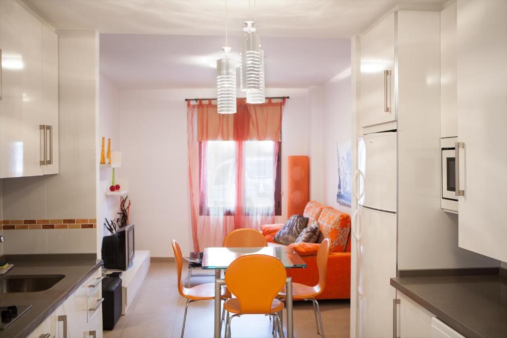 cocina con mesa, sillas y sofá en Real de Cartuja Apartments & Suites en Granada