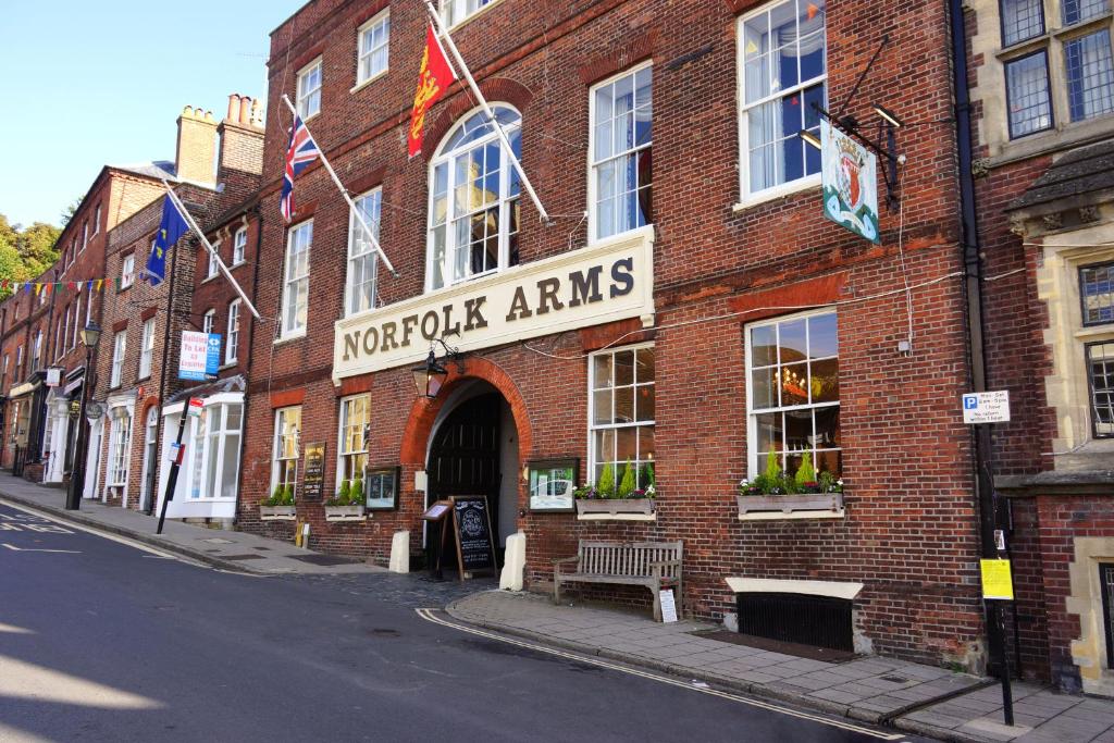 ein Backsteingebäude mit einem Schild, das gemeinnützige Waffen liest in der Unterkunft Norfolk Arms Hotel in Arundel