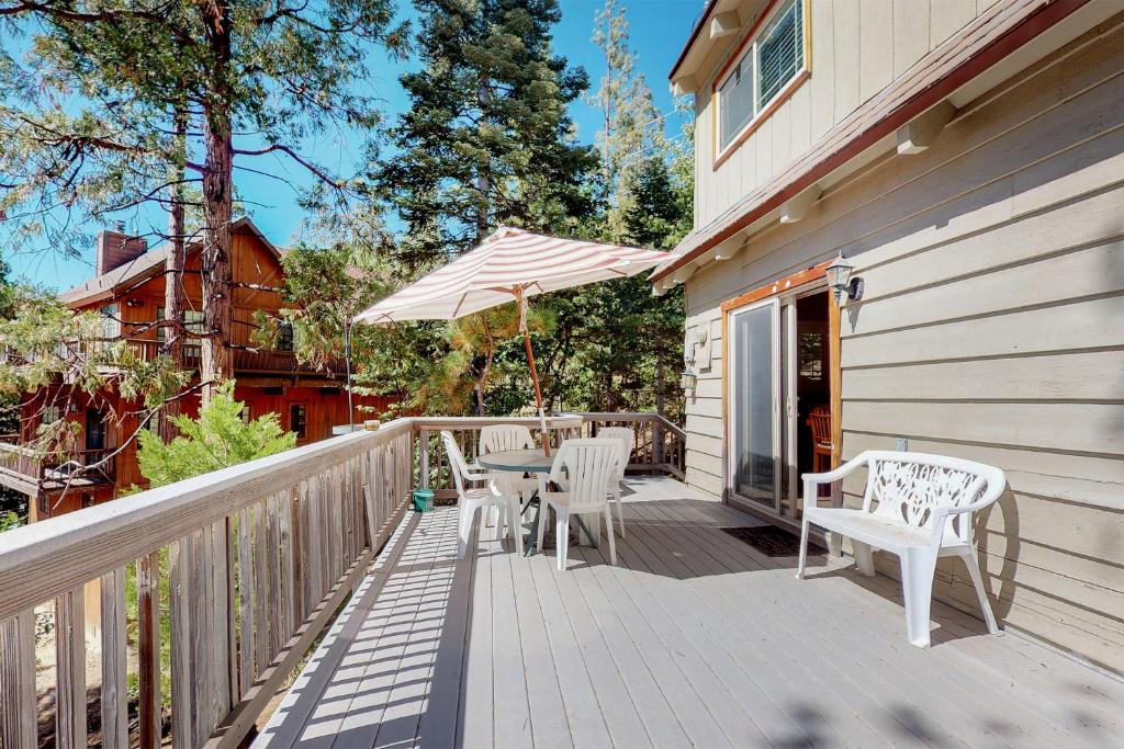 a wooden deck with chairs and an umbrella at Dancing Bear Chalet in Lake Arrowhead