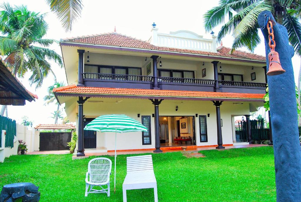 a house with two chairs and an umbrella in the yard at Wintergreen Water Front Resort in Tripunnittara