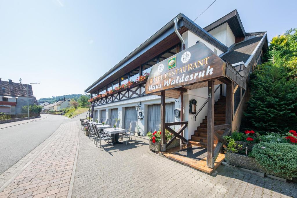 ein Gebäude mit Tischen und Stühlen auf einer Straße in der Unterkunft Hotel Restaurant Haus Waldesruh in Eppenbrunn