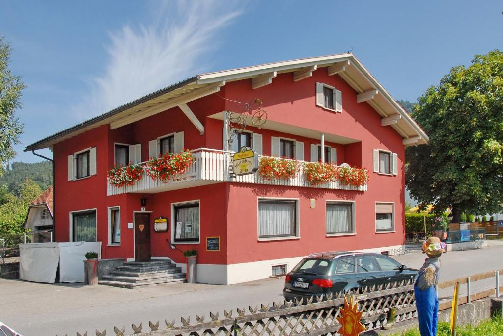 un edificio rojo con un coche aparcado delante de él en Wirtshaus zum Stern en Satteins