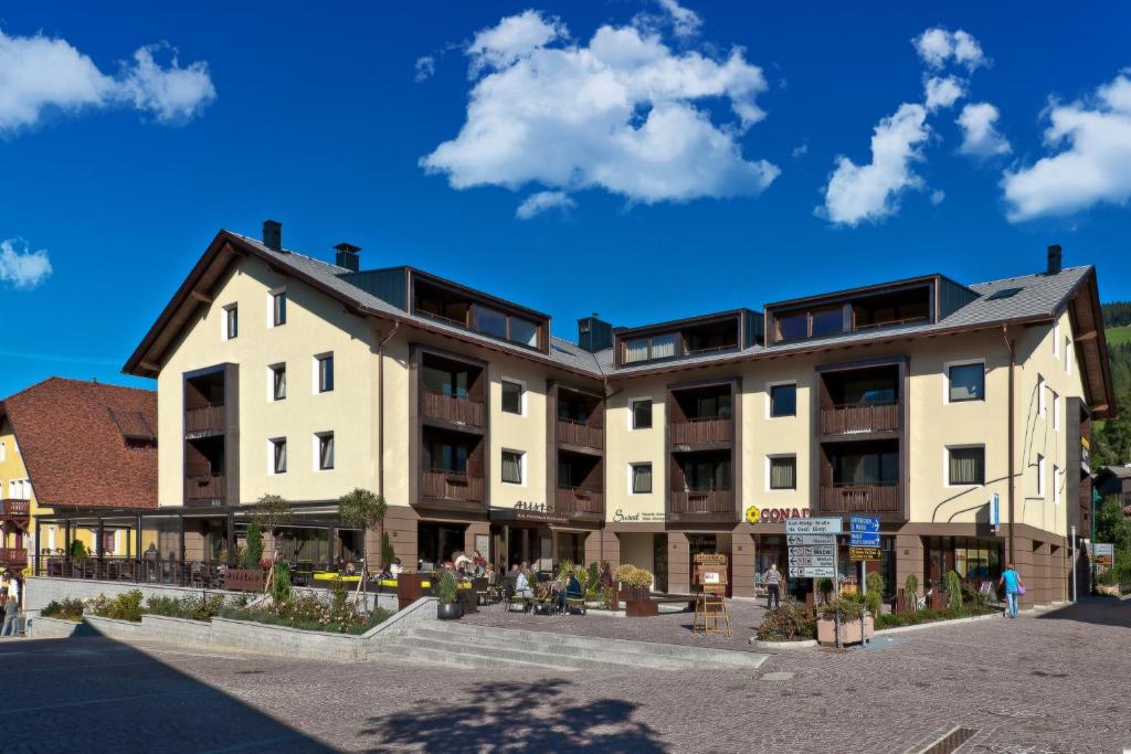 un edificio con gente caminando delante de él en Ariston Dolomiti Residence, en Dobbiaco